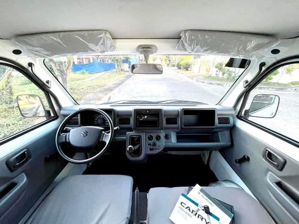Cab of the Suzuki Carry with new seat covers and the manual on the seat